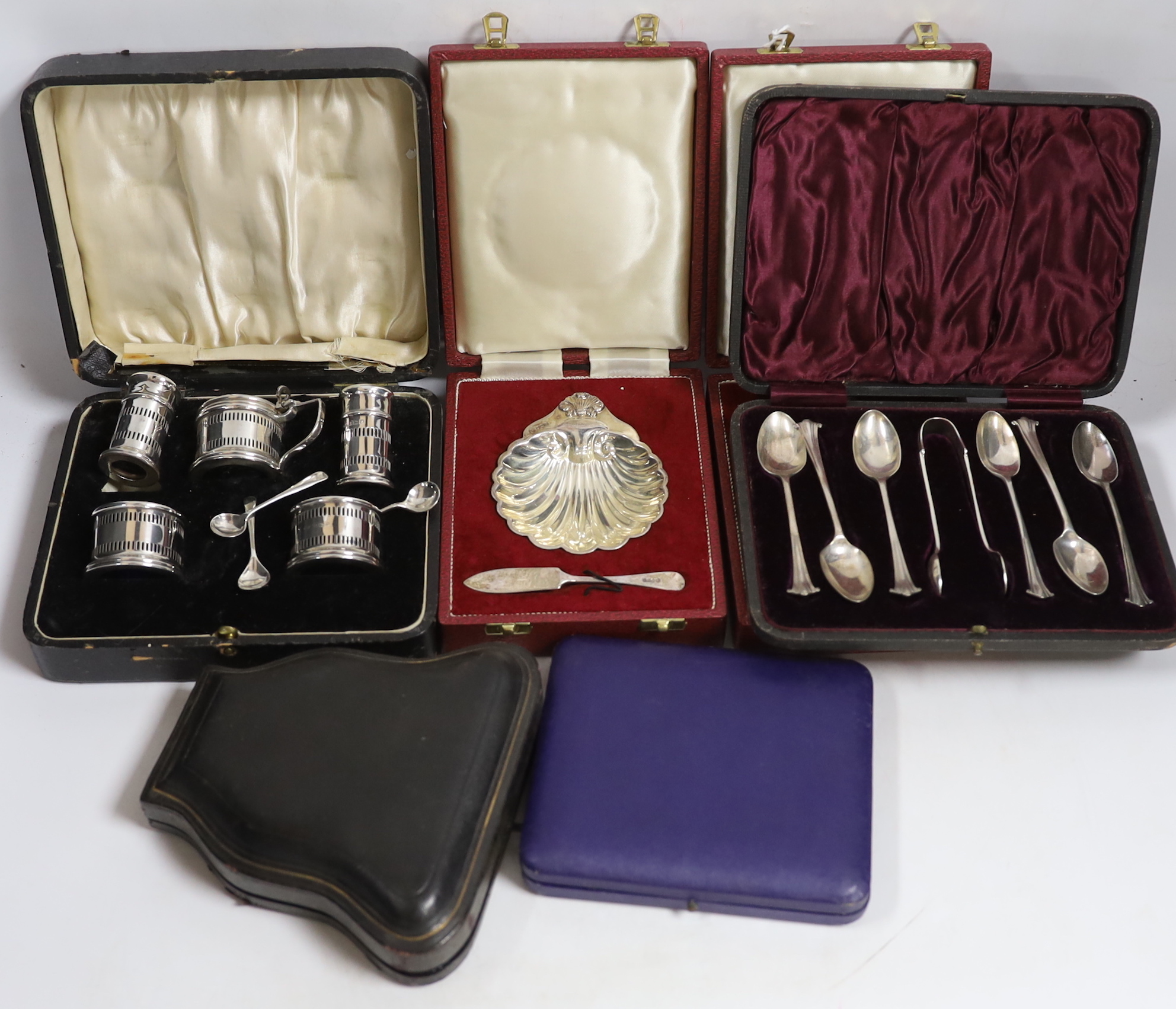 Two modern silver cased shell and butter knife sets, a cased silver five piece condiment set, a cased set of six silver teaspoons with tongs, one other cased silver butter shell and knife and a cased set of plated teaspo